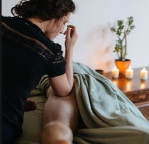 Tristin working with a draped client in a candlelit room